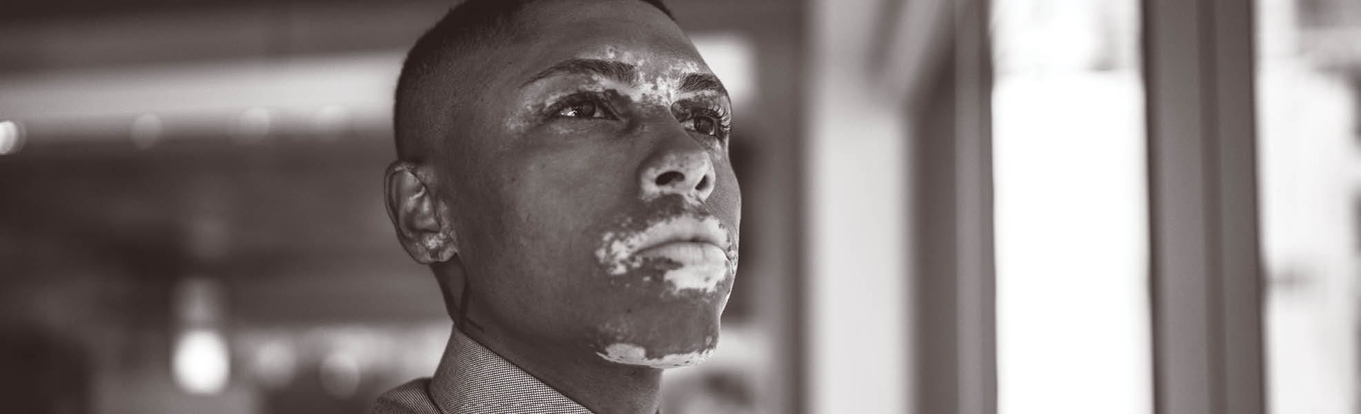 Businessman looking through window contemplating and thinking on the office