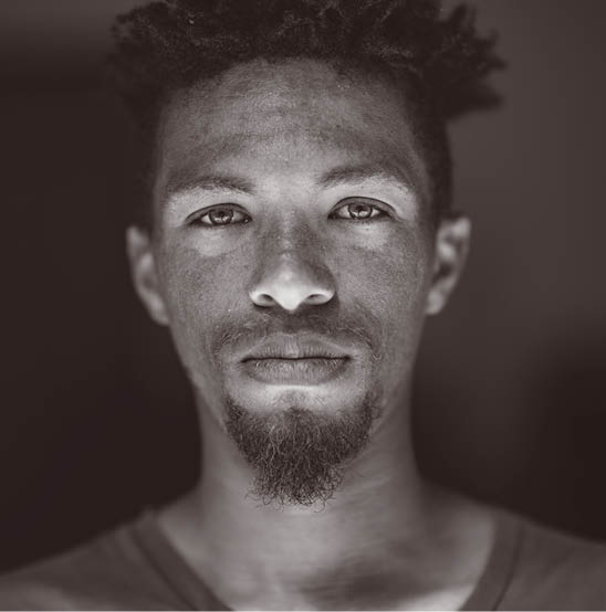 Close up Headshot Portrait of young mixed race male face with green eyes facial hair and rasta hair